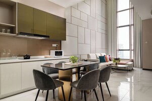 A modern kitchen with a central island, grey chairs, and a dining table.