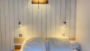 A bed with white bedding, two bedside tables, and wall-mounted lamps.