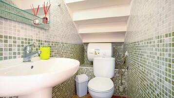 Un baño con lavamanos, inodoro y estante de vidrio con espejo.