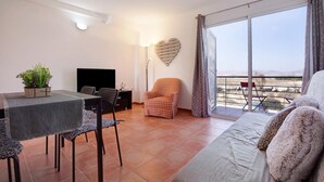 A living room with a sofa, a dining table, and chairs, a heart-shaped wall decoration, and a balcony with a view. - Casa Aripauso with Shared Pool, Private Terrace, Sunset Views and Wi-Fi (Nuevo Hoirzonte)