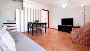 A living room with a sofa, a dining table with chairs, a TV, and a staircase. - Casa Aripauso with Shared Pool, Private Terrace, Sunset Views and Wi-Fi (Nuevo Hoirzonte)