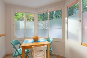 Un comedor con una mesa, sillas y ventanas con vidrio esmerilado.