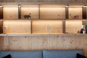 Un mur en bois, agrémenté d’étagères où sont exposés des objets décoratifs, et un canapé placé devant.