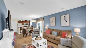 A living room with a sofa, coffee table, and a dining area with chairs and a table.