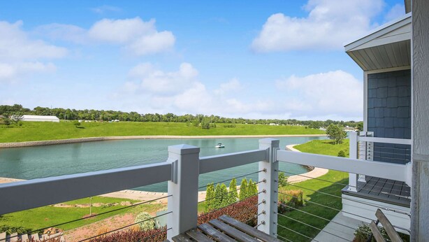 Ein Balkon mit Blick auf einen Fluss, ein Boot und eine grüne Landschaft.