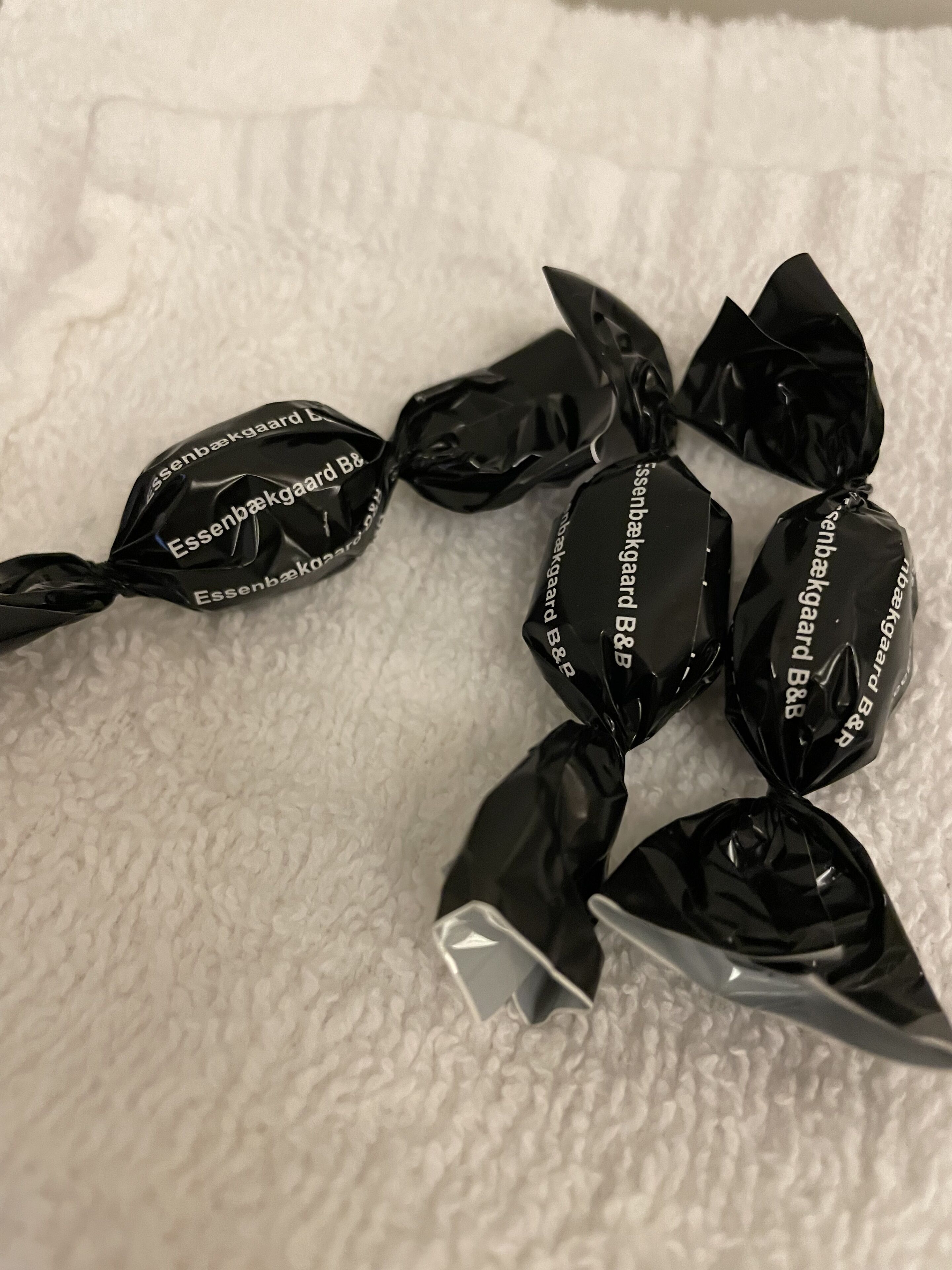 Several wrapped candies on a textured white surface.