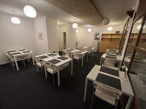 A dining area with multiple tables and chairs, a refrigerator, and a window with plants. - Essenbaekgaard B&B (Randers)