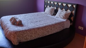 Un letto con una coperta e cuscini a motivi decorativi, una testiera con un design geometrico e una finestra vista verde.