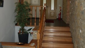 Una scala con gradini in legno e una ringhiera rossa, che porta a una porta con un pannello di vetro.