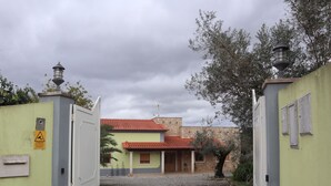 Un cancello chiuso conduce a un edificio con un vialetto acciottolato che porta a una porta.