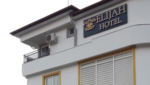 Exterior del Hotel Eliah con una entrada destacada, un balcón y un cartel con la dirección.