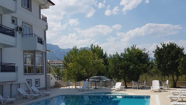 Una piscina con sillas de descanso y un edificio con balcones.