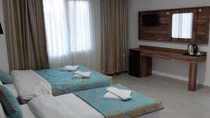 Habitación de hotel con dos camas, un escritorio, un televisor y una cafetera.