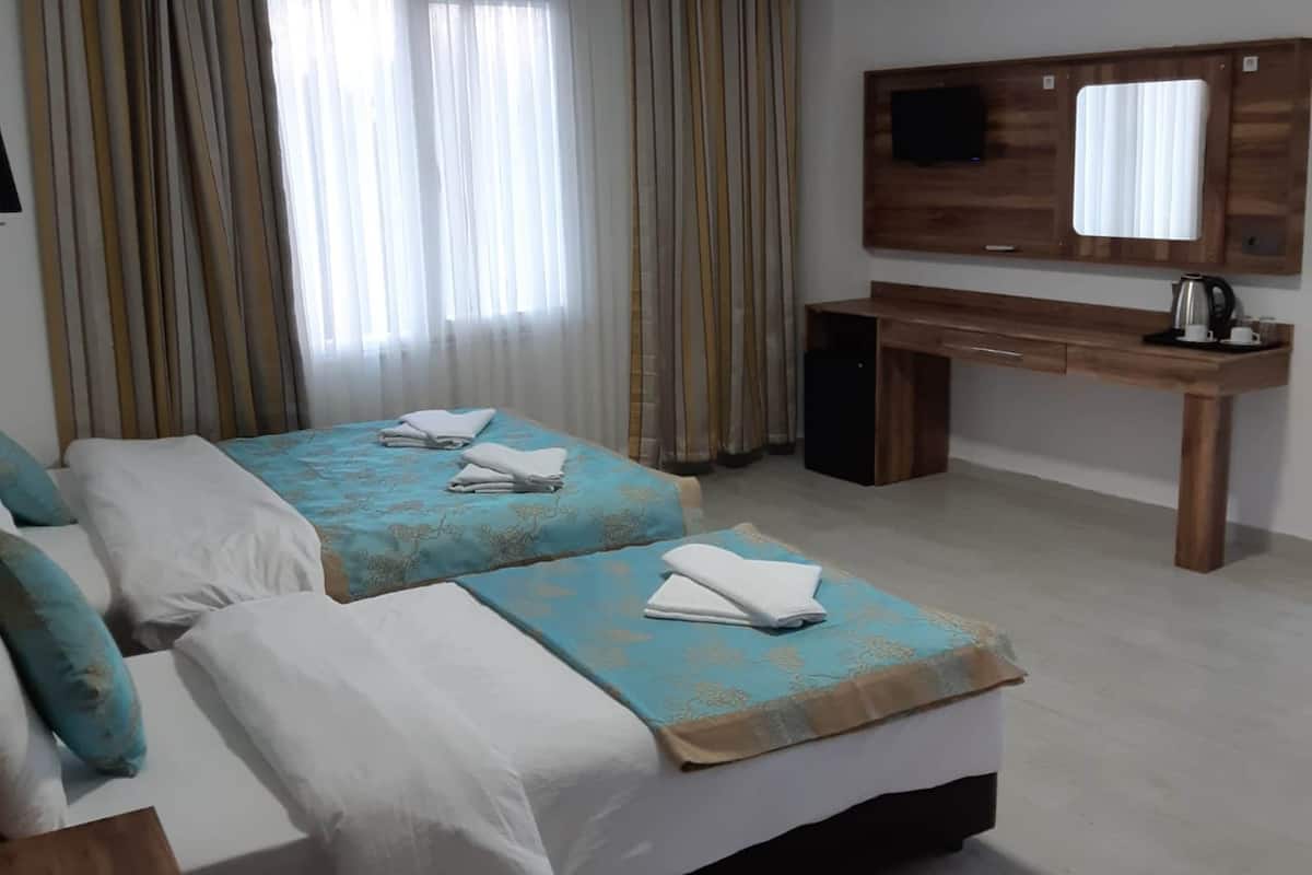 Habitación de hotel con dos camas, un escritorio, un televisor y una cafetera.