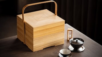 A wooden chest with a handle, a small hourglass, and a teapot on a table.