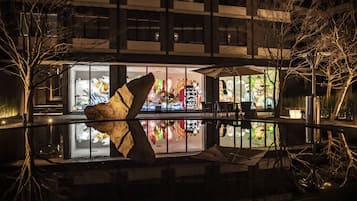 A nighttime view of a building with a glass facade reflecting colorful interior decorations.