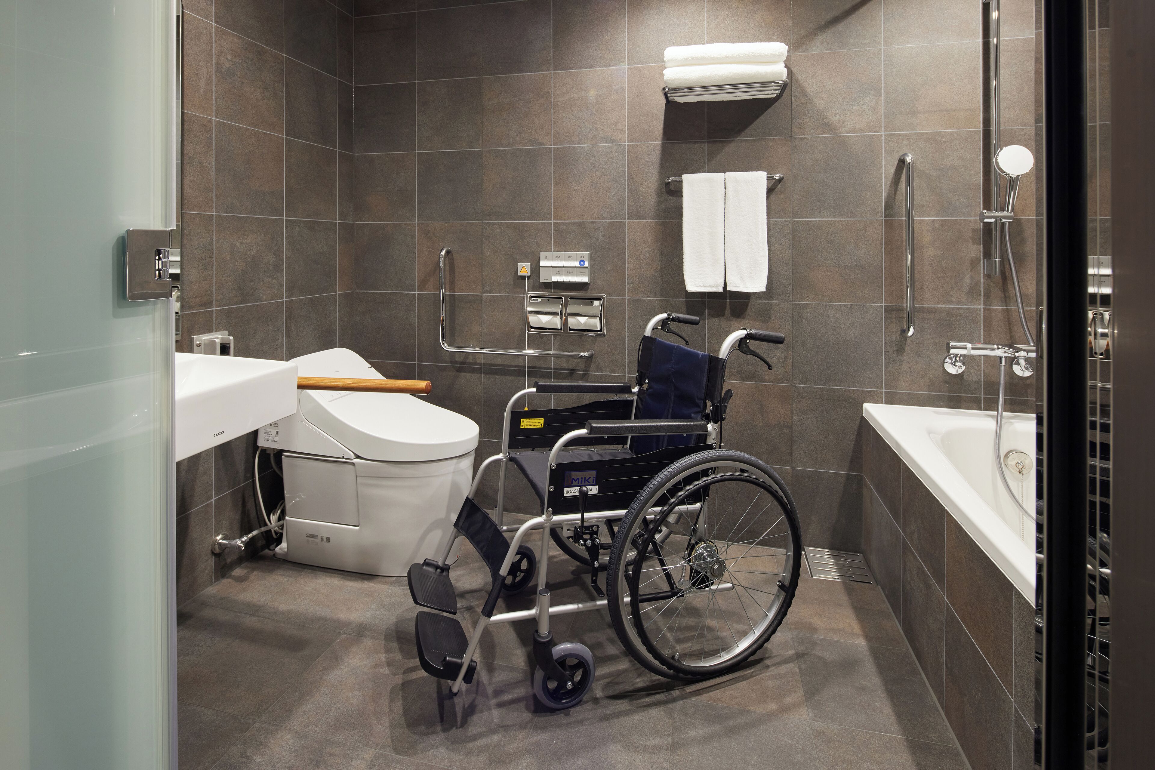 Un baño moderno con ducha accesible para sillas de ruedas, lavamanos y retrete.