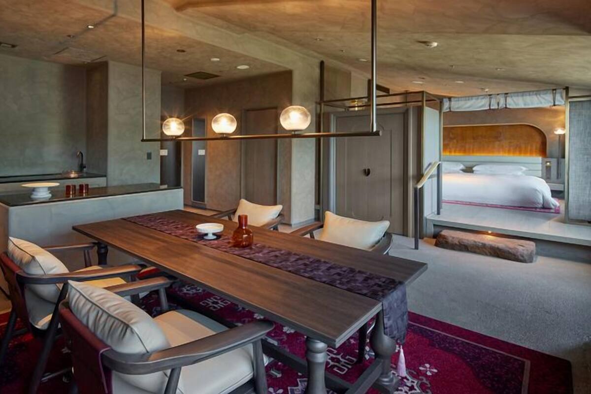 Ein modernes Hotelzimmer mit Essbereich, einem Bett mit Blick und einer Küchenzeile.