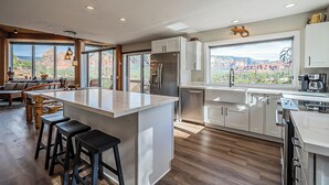 Une cuisine moderne dotée d’un grand îlot central, de tabourets de bar et offrant une vue sur des formations rocheuses rouges.
