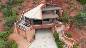 Une maison moderne à deux étages, dotée d’une grande terrasse, d’un patio couvert et d’un escalier menant à l’entrée principale.