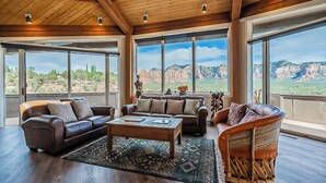 Un salon spacieux doté d’une grande fenêtre donnant sur un paysage montagneux, et aménagé avec des canapés en cuir et une table basse.