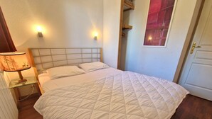 A bedroom with a large bed, a nightstand with a lamp, a wooden headboard, and a door with a mirror.