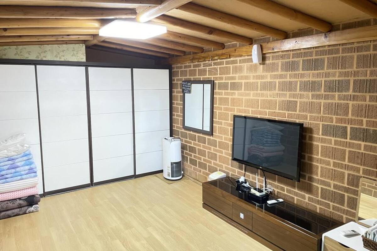 Habitación con pared de ladrillo, televisor de pantalla plana montado en la pared, techo de madera y suelo de madera.