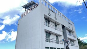 A multi-story building with a flat facade, large windows, and a balcony on the upper floor. - Sokcho Haeoleumhouse (Sokcho)