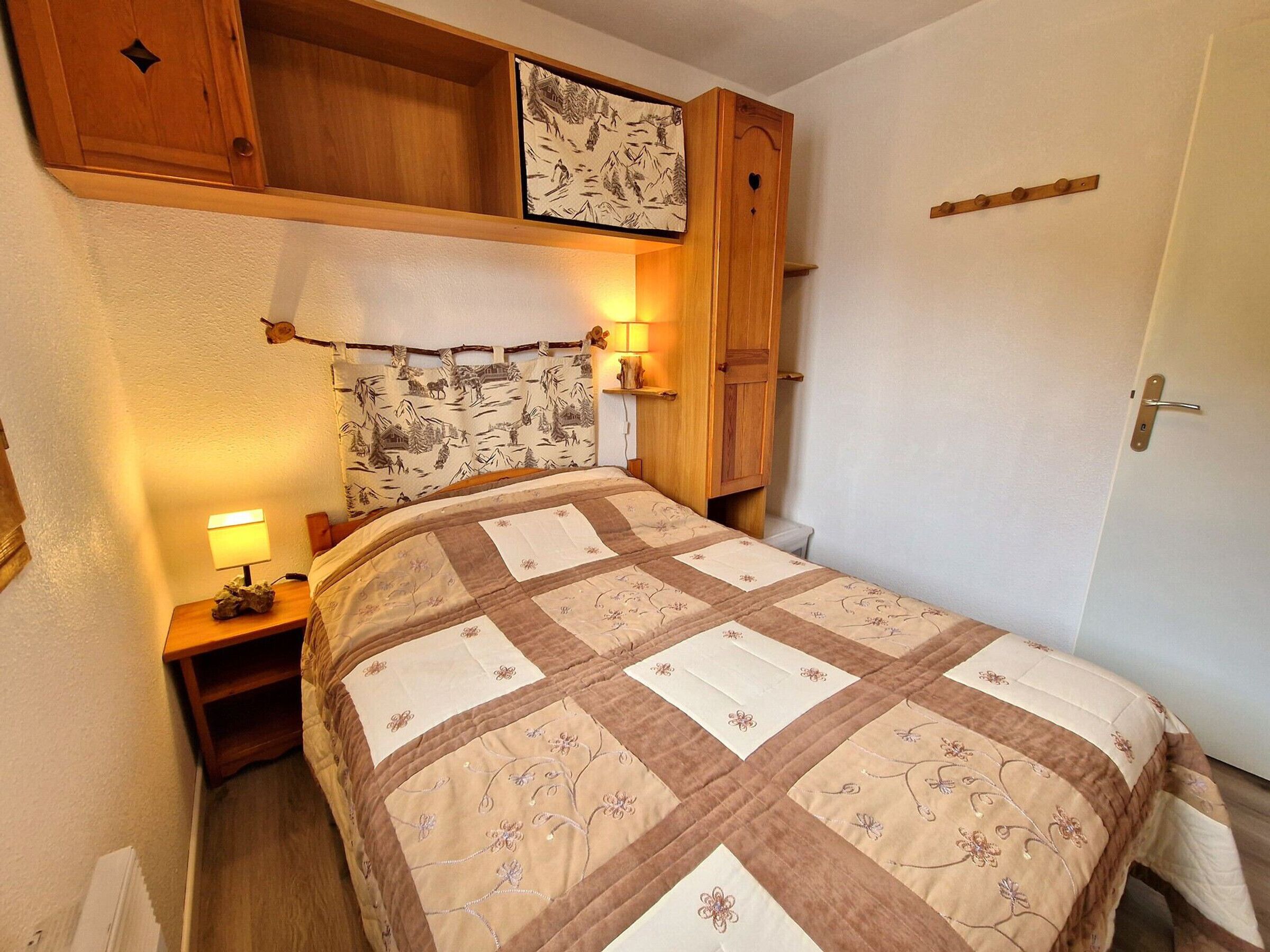 Una camera da letto con un letto, una testiera in legno, abat-jour e una porta.