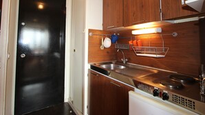 Une cuisine de taille réduite, dotée de meubles en bois, d’un évier en acier inoxydable et d’une cuisinière intégrée.