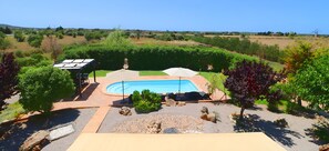Une piscine entourée d’une terrasse, agrémentée d’une pergola et offrant une vue sur la campagne.