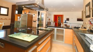 A modern kitchen with a central island, built-in appliances, and a glass partition. - Son Vigili 417 magnificent villa with private pool, jacuzzi, children's area and air-conditioning (Campos)