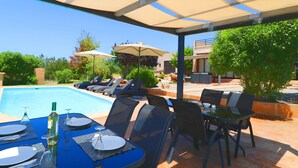 A poolside area with a table set for dining, lounge chairs, and umbrellas. - Son Vigili 417 magnificent villa with private pool, jacuzzi, children's area and air-conditioning (Campos)