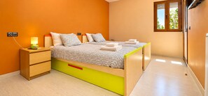 Een slaapkamer met een bed, nachtkastje, lamp en een raam met uitzicht.