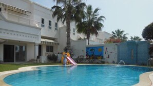 A swimming pool with a slide, palm trees, and a building with a mural. - Prestigious villa in monastir (Monastir)