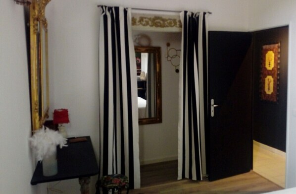 A room with a black and white striped curtain, a mirror, and a door with a light fixture.