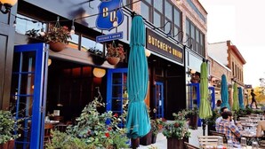 Un espace extérieur aménagé avec des tables et des chaises, un auvent bleu et des jardinières suspendues.