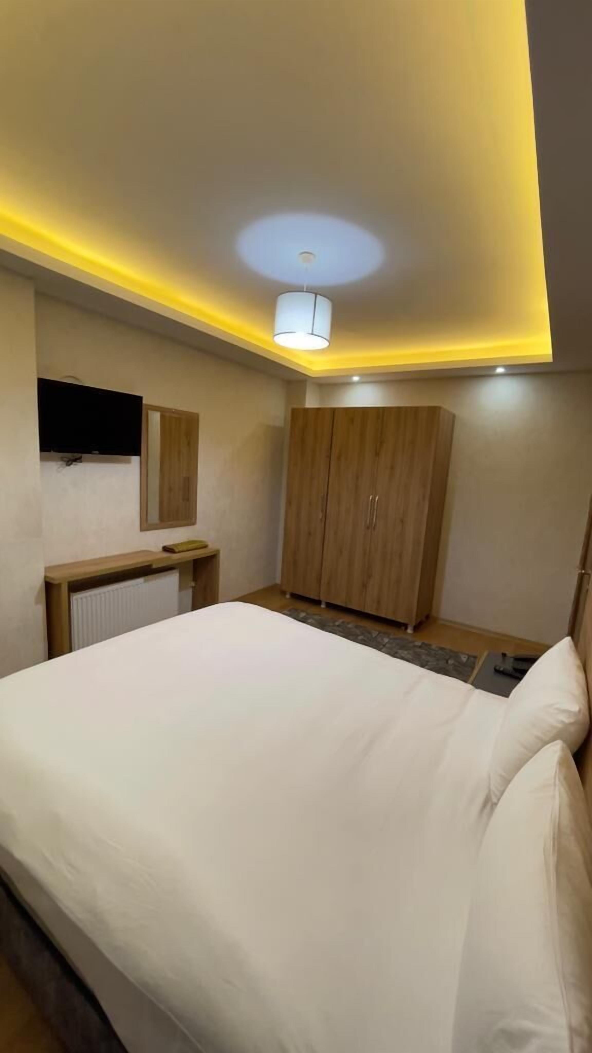 A bedroom with a bed, a wardrobe, a mirror, and a ceiling light.