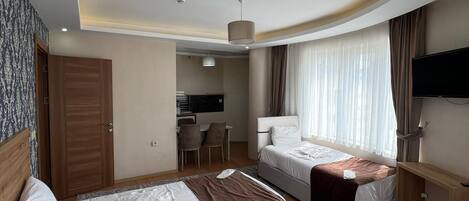 Habitación de hotel con dos camas, un escritorio, una silla, un televisor y una ventana con cortinas.