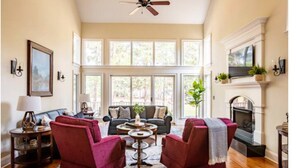 A spacious living room with a fireplace, large windows, and a ceiling fan. - Million Dollar View w/ 3 masters + Peloton on Pinehurst No. 9 (Pinehurst)