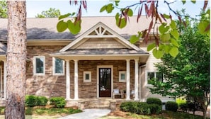 A two-story house with a stone facade, a front porch with columns, and a well-maintained lawn. - Million Dollar View w/ 3 masters + Peloton on Pinehurst No. 9 (Pinehurst)