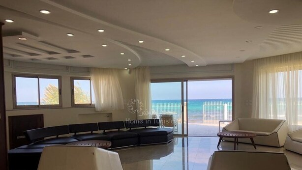 Un salón amplio con un sofá modular curvo, una mesa de centro y vistas al mar.