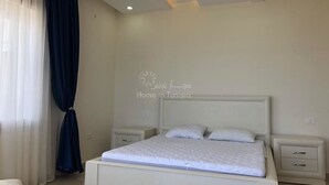 Un dormitorio con cama, mesitas de noche y estante en la pared.