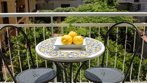 A balcony with a table and two chairs, a plate with lemons, and a view of buildings and greenery. - A Queen's room with Balcony (Sorrento)