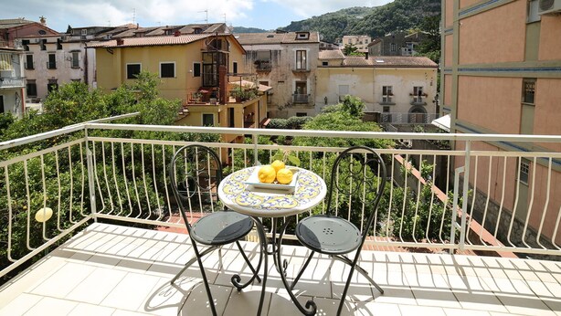 A balcony with a table and two chairs, overlooking a residential area with terraced houses. - A Queen's room with Balcony (Sorrento)