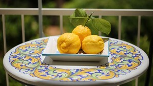 A table with a decorative plate holding three lemons and a leaf. - A Queen's room with Balcony (Sorrento)