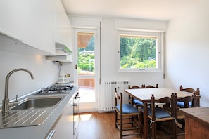 A kitchen with a sink, stove, and dining table with chairs.