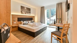 A modern hotel room with a large bed, a wooden desk, and a dining table. - Chalet in the Alpine Lodge Klösterle (Klösterle am Arlberg)