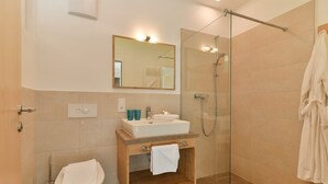 A modern bathroom with a glass-enclosed shower, a sink with a mirror above it, and a toilet. - Chalet in the Alpine Lodge Klösterle (Klösterle am Arlberg)