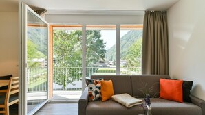 A modern living room with a sofa, a coffee table, and a view of a balcony with a railing. - Chalet in the Alpine Lodge Klösterle (Klösterle am Arlberg)
